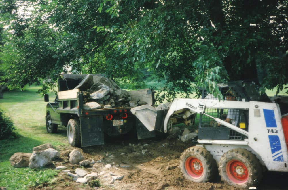 Broken concrete patio pieces stacked on a lawn during small slab demolition